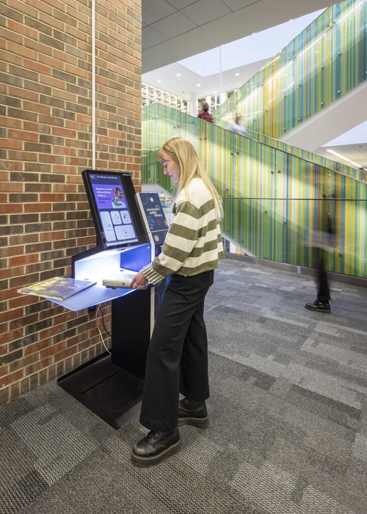 A woman uses the Bibliotheca selfCheck 1000 kiosk to check out books at the Cincinnati & Hamilton County Public Library.