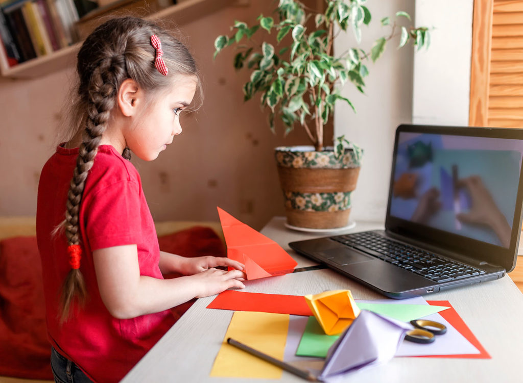 Young girl learning how to make paper shapes watching a video