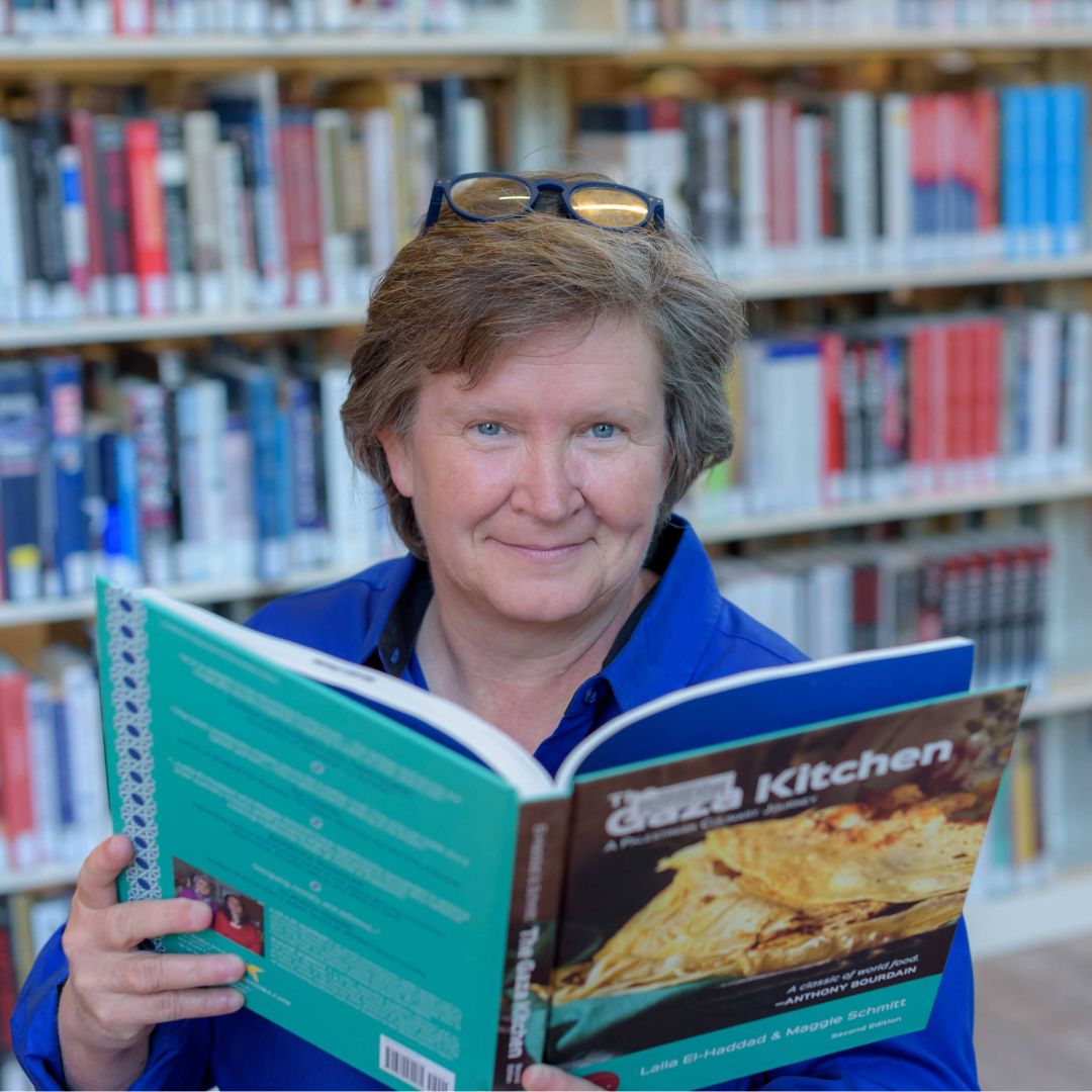 Lori Livesay from Bibliotheca in a library, holding an open book in her hands
