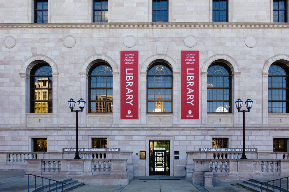 Exterior view of the George Latimer Central Library in St. Paul, Minnesota, with red vertical banners reading "Library".